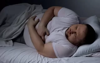 Overweight man suffering from fatty liver disease, showing liver discomfort at nigh